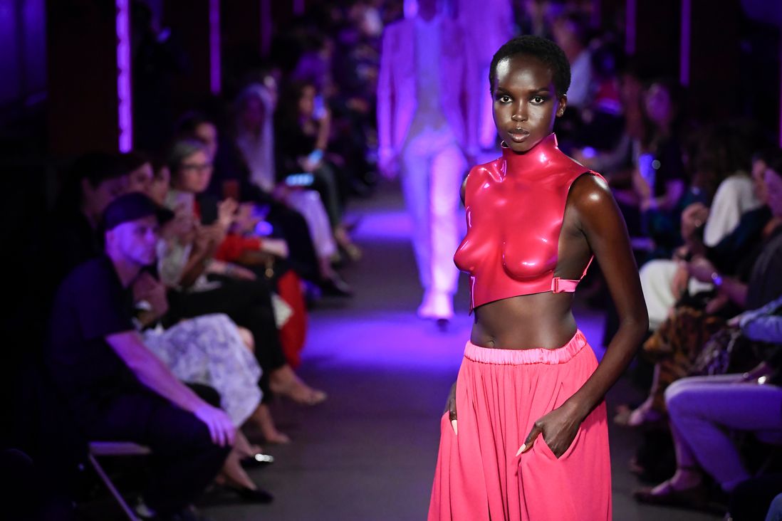 A model wearing a skintight deep pink top and pants walks the catwalk